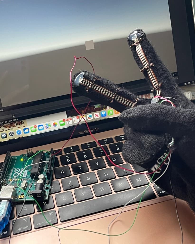 Glove with flex sensors wired to an Arduino, controlling a cube in Unity on a laptop